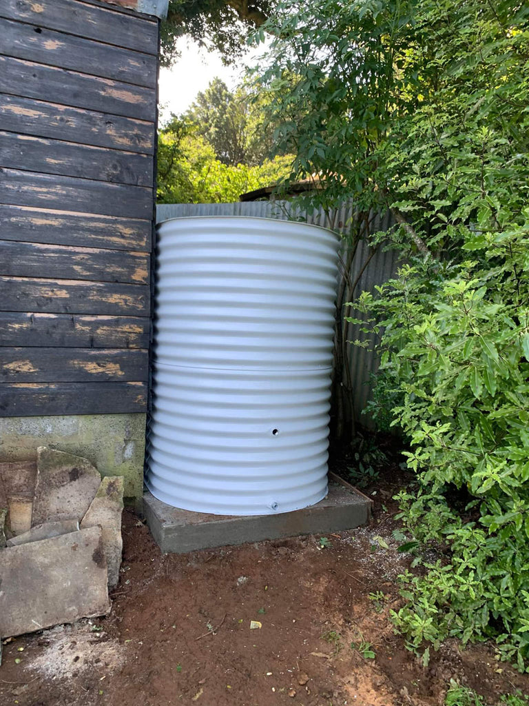 small steel surfmist water tank next to a house