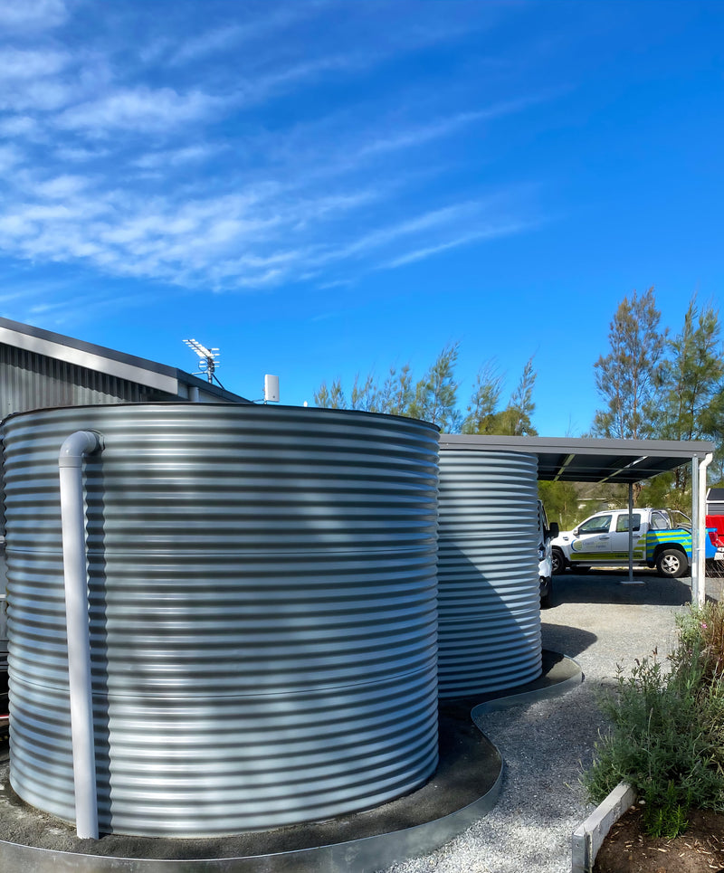 two ccwt round water tanks on a fancy sculpted pad with a ute in the background